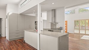A modern kitchen with white cabinetry, a central island, and a large window providing natural light.