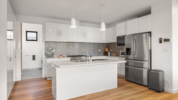 Una cocina moderna con armarios blancos, un refrigerador de acero inoxidable y una isla central.