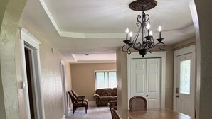 A dining area with a wooden table and chairs, a chandelier, and a view into another room with a couch and chairs. - 8 beds-Great deal! (Willmar)