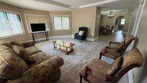 A living room with a sectional sofa, two armchairs, a coffee table, a TV on a stand, and a green armchair. - 8 beds-Great deal! (Willmar)