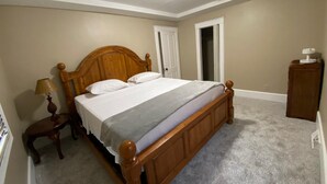 A bedroom with a wooden bed, a nightstand, a lamp, a door, and a small cabinet. - 8 beds-Great deal! (Willmar)
