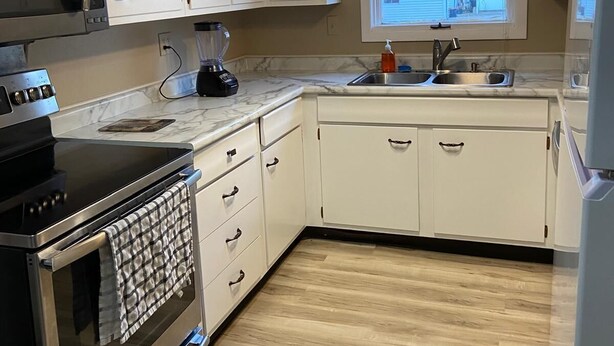 A kitchen with white cabinets, a stainless steel oven, a microwave, and a sink. - 8 beds-Great deal! (Willmar)
