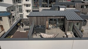 Una terraza en la azotea con jacuzzi, mobiliario exterior y vistas a la ciudad.