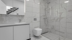 Un baño moderno con piso de mármol, un lavamanos blanco, inodoro y ducha.