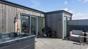 Un patio con un jacuzzi, una parrilla y mobiliario exterior.