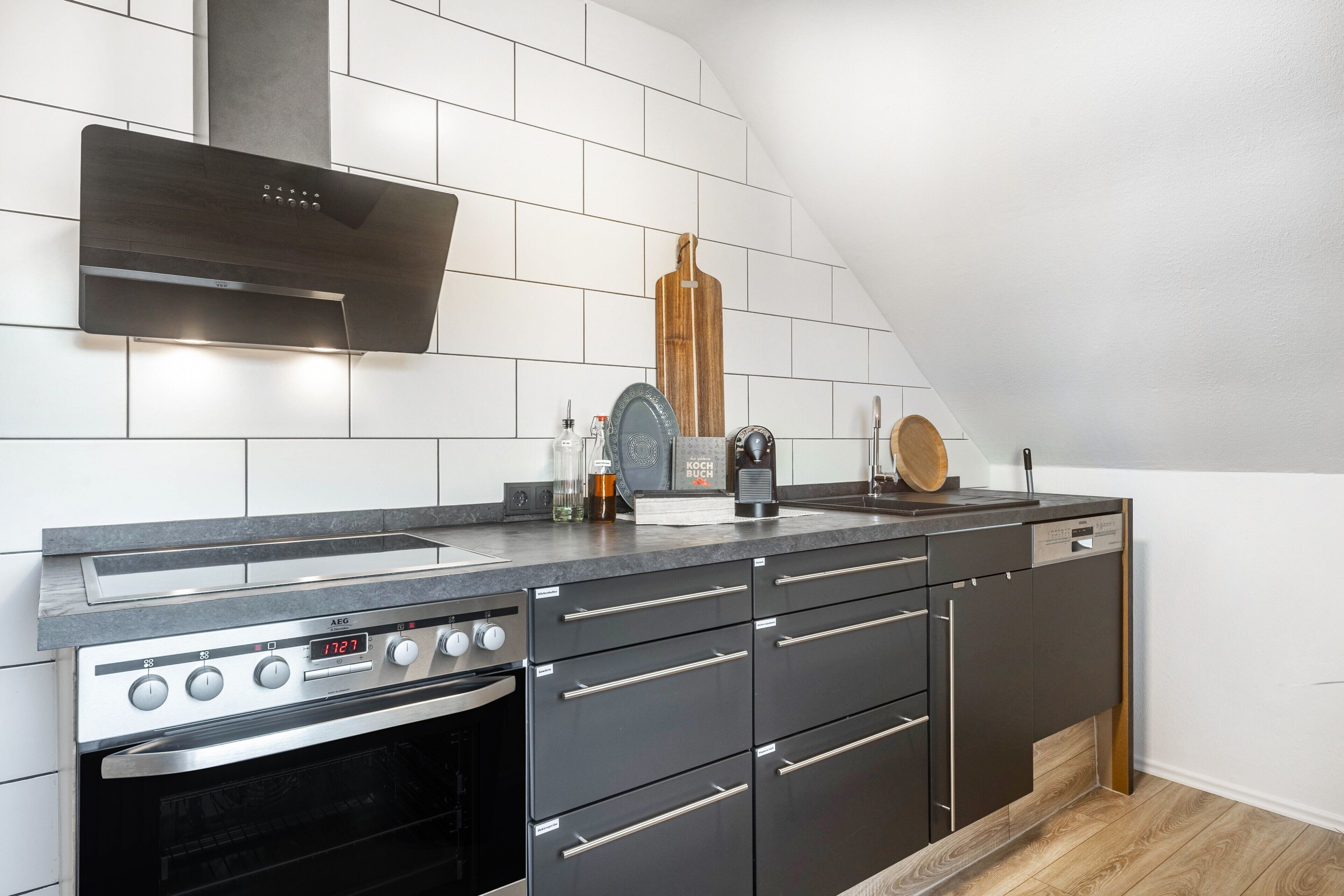 A modern kitchen with a built-in oven, stainless steel cabinets, and a digital clock displaying the time.