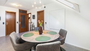 Un salón de conferencias con una mesa redonda, cuatro sillas, un jarrón con flores y una pizarra en la pared.