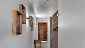 A hallway with a wooden door, a bench, and framed pictures on the wall.