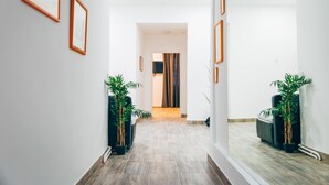 A hallway with framed pictures on the walls, potted plants, and a view into another room. - Comfy Hotel room | Mariahilfer Str (Vienna)
