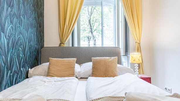 A bed with white bedding, a grey headboard, and two beige pillows. - Comfy Hotel room | Mariahilfer Str (Vienna)