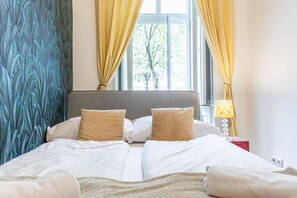 Ein Bett mit weißer Bettwäsche, einem grauen Kopfteil und zwei beigen Kissen.