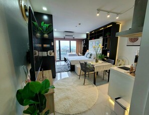 A modern bedroom with a bed, bedside table, and a view of the city. - Incredible Makati Studio Unit/Stunning view &70"TV (Makati)