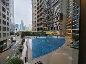 A residential building with a swimming pool, surrounded by high-rise buildings. - Incredible Makati Studio Unit/Stunning view &70"TV (Makati)