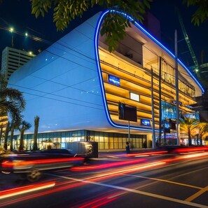 A modern building with a curved facade, large windows, and a blue neon outline. - Incredible Makati Studio Unit/Stunning view &70"TV (Makati)