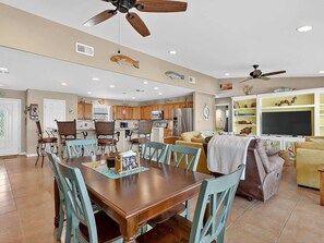 A spacious living area with a dining table, chairs, a sofa, and a TV.