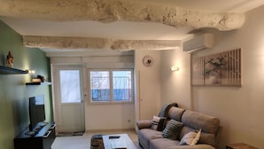 A living room with a sofa, a coffee table, a TV, and a door leading to a balcony. - AIMARGUES HOUSE 20 MN FROM THE SEA IDEAL FOR VACATIONS OR BUSINESS TRIPS (Aimargues)