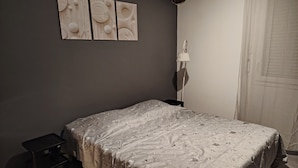 A bedroom with a bed, a nightstand, a lamp, and a wall-mounted artwork. - AIMARGUES HOUSE 20 MN FROM THE SEA IDEAL FOR VACATIONS OR BUSINESS TRIPS (Aimargues)