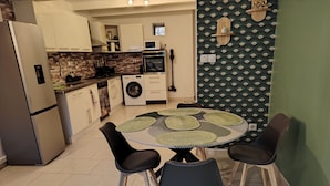 A modern kitchen with a built-in washing machine, a microwave, and a stove. There is a dining table with four chairs. - AIMARGUES HOUSE 20 MN FROM THE SEA IDEAL FOR VACATIONS OR BUSINESS TRIPS (Aimargues)