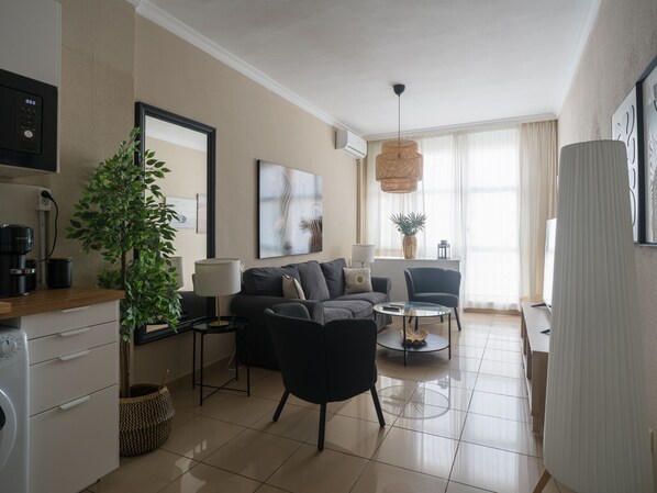 A modern living room with a sofa, armchairs, a coffee table, and a large window with curtains.