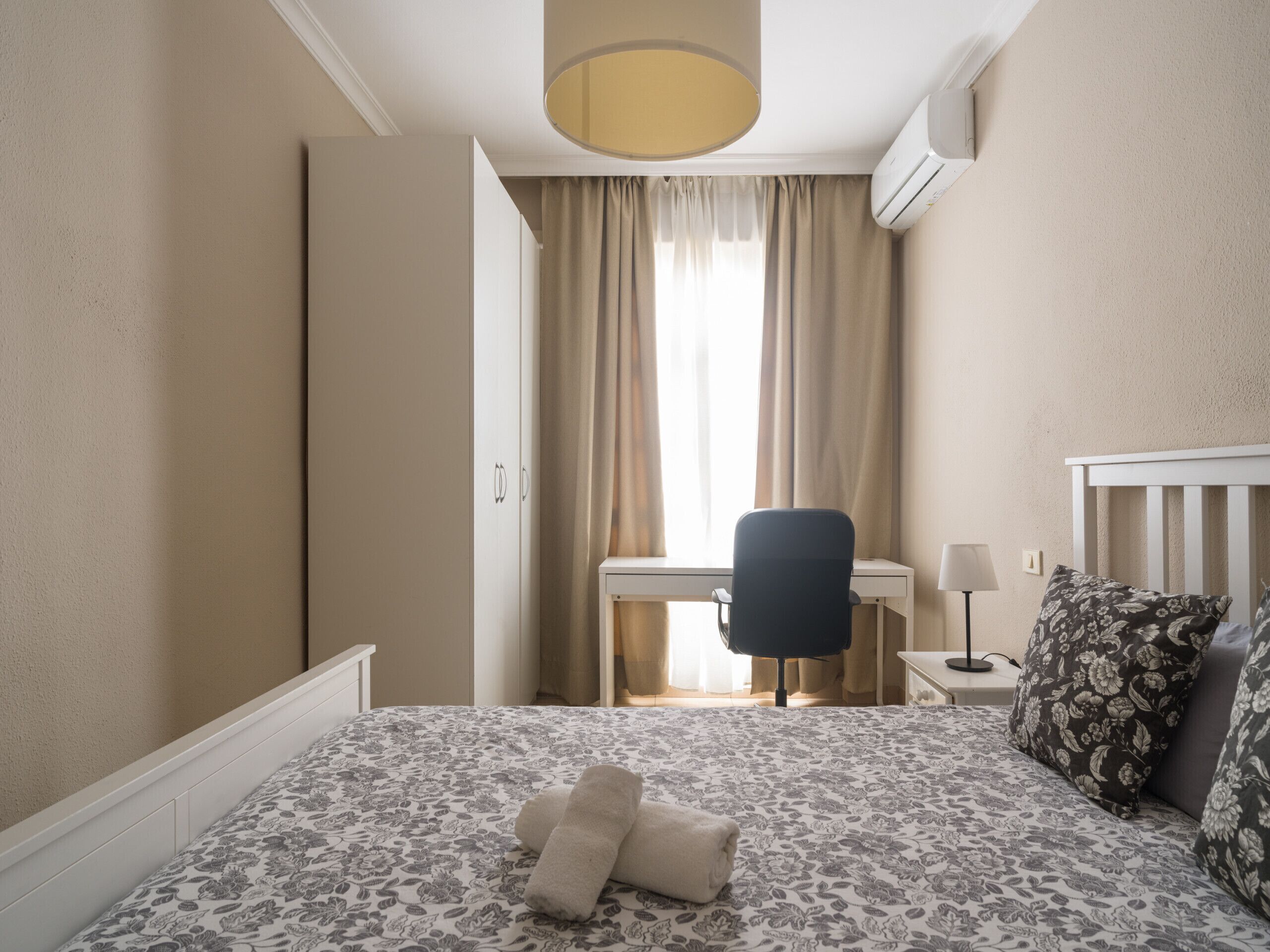 Una habitación de hotel con una cama, un escritorio, una silla y una ventana con cortinas.