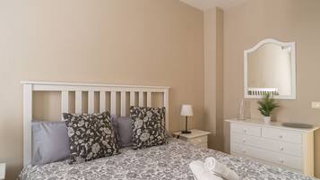 A bedroom with a bed, a nightstand, a dresser, a mirror, and a lamp.