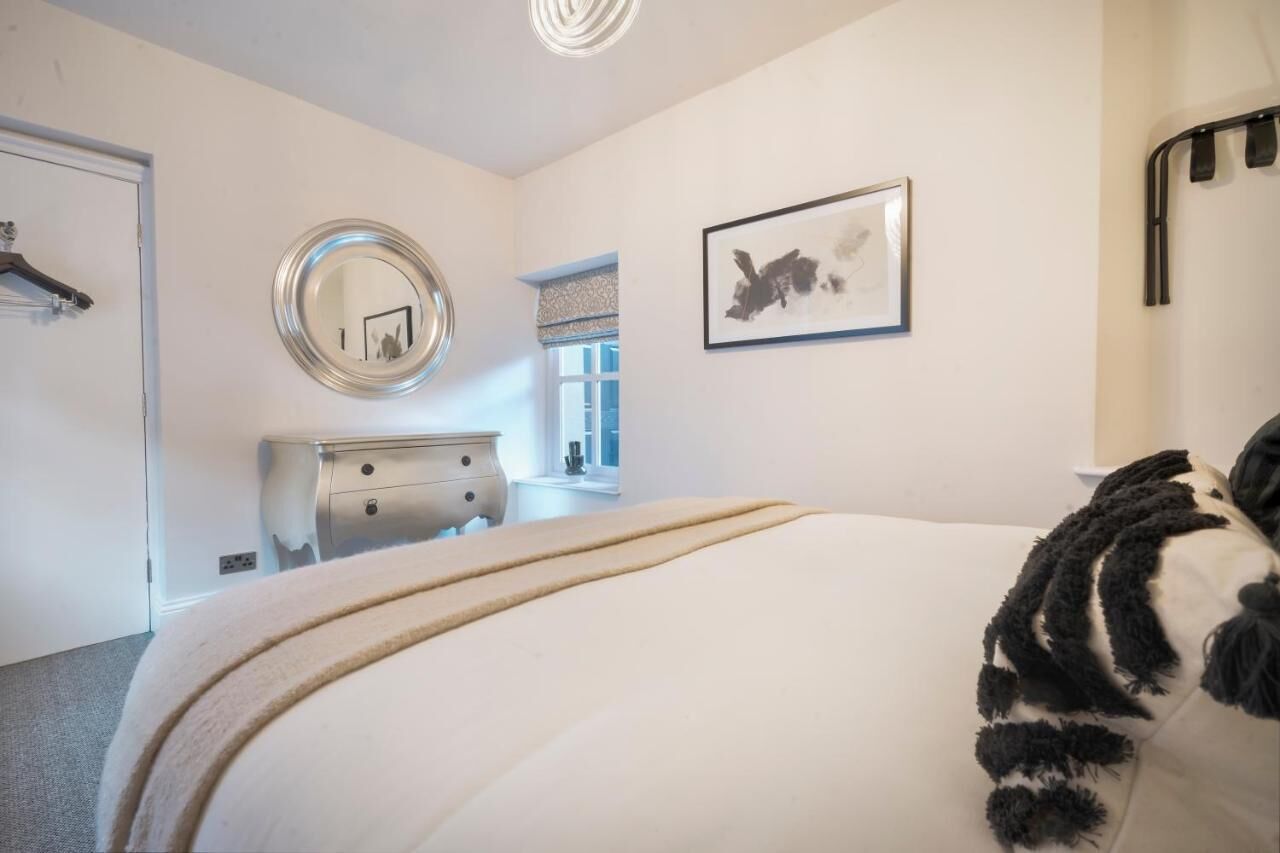 A bedroom with a bed, dresser, mirror, and artwork on the wall.