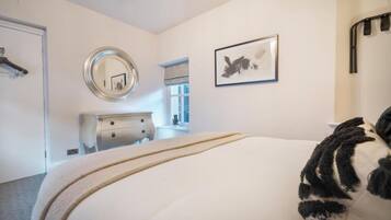 Un dormitorio con cama, cómoda, espejo y obras de arte en la pared.