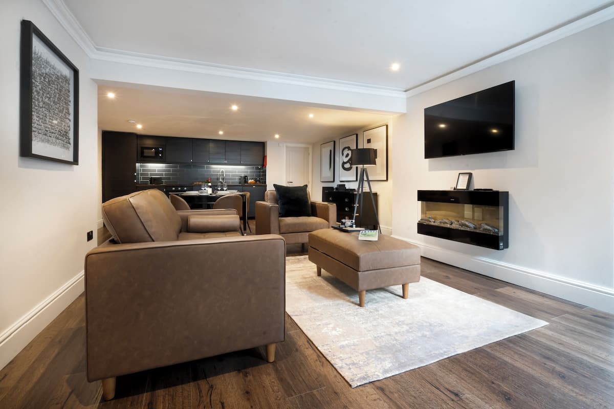 Una sala de estar moderna con un sofá, un reposapiés y una chimenea.