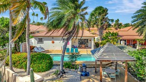 A residential area with a swimming pool, patio furniture, and palm trees.