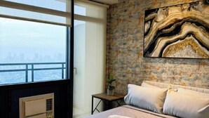 Ein modernes Schlafzimmer mit großem Bett, Blick auf die Stadt und einer Steinwand mit Marmorbildkunst.