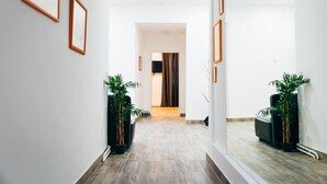 Un pasillo con cuadros en las paredes, plantas en macetas y vistas a otra habitación.