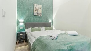 Un dormitorio con cama, mesitas de noche, una lámpara de pared y un cuadro enmarcado.