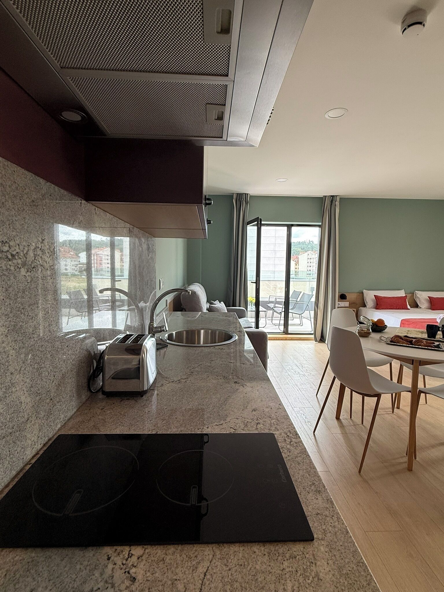 Een moderne keuken met een ingebouwde kookplaat, een spoelbak en een eetgedeelte met een tafel en stoelen.