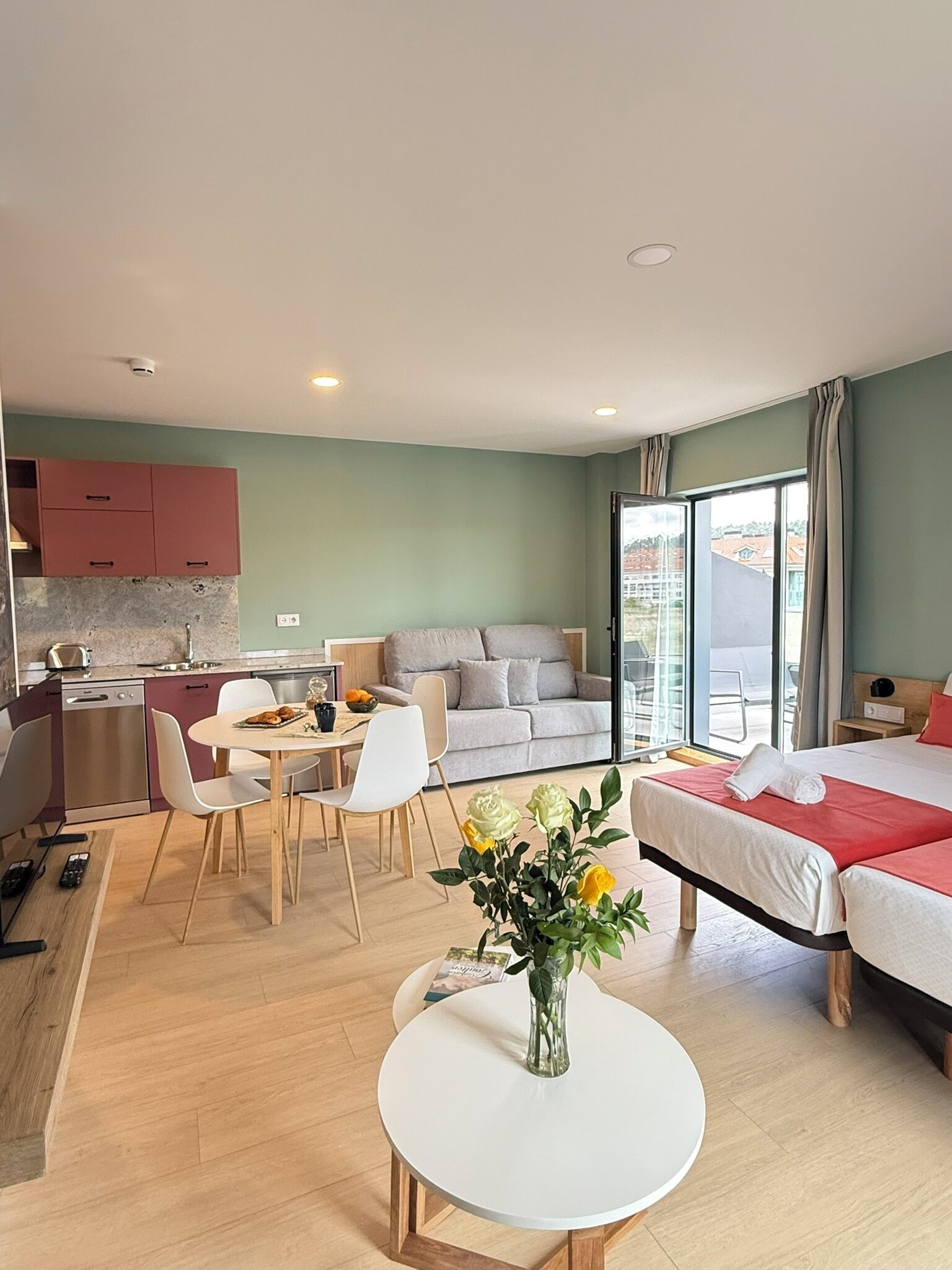 Una habitación de hotel moderna con kitchenette, comedor, sofá y cama.