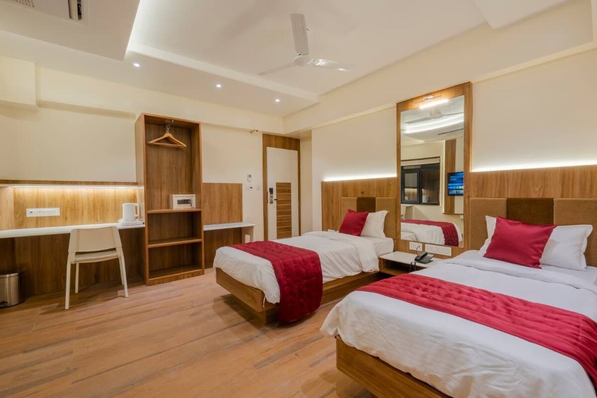 Een hotelkamer met twee bedden, een bureau, een stoel en een kledingkast.
