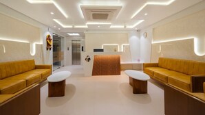 Een moderne hotellobby met twee banken, een receptiebalie en een wachtruimte.