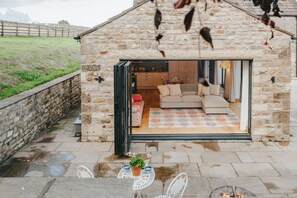 A stone building with a glass door leading to a furnished interior. - New Peaceful Countryside Annex (Leyburn)
