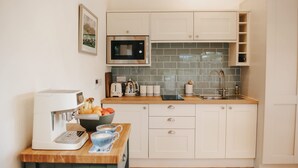 A compact kitchen with white cabinets, a microwave, a coffee machine, and a sink. - New Peaceful Countryside Annex (Leyburn)