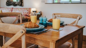 A wooden dining table with two plates, two glasses of orange juice, and two croissants. - New Peaceful Countryside Annex (Leyburn)