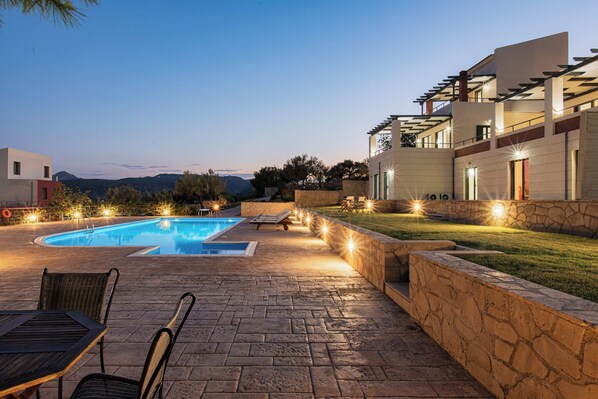 A swimming pool with a stone deck, lounge chairs, and a view of mountains.