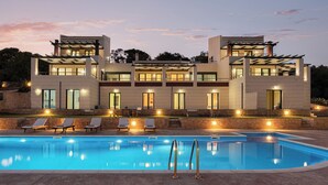 A modern two-story house with a swimming pool, outdoor seating, and a stone wall. - Aphaias Residence Two, Aphaias Villas (Aegina)