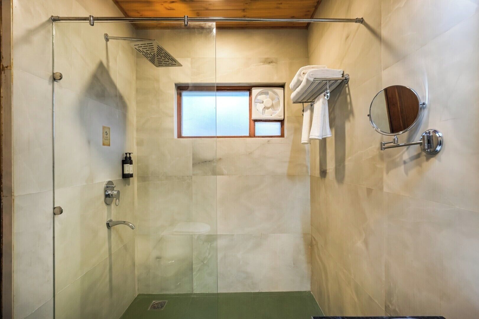A walk-in shower with a glass door, a small window, a towel rack, and a mirror.