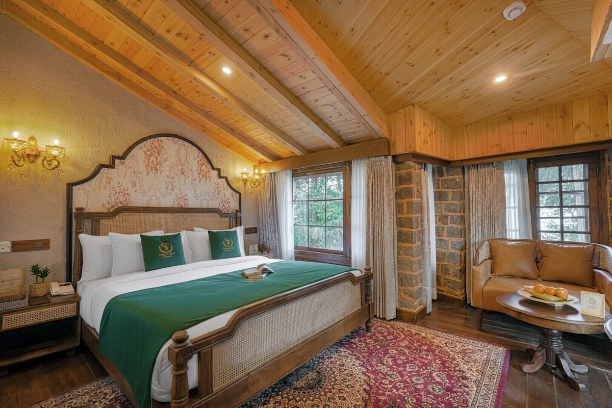 Una habitación con paneles de madera, una cama grande, un sofá de madera y una pequeña mesa con fruta.