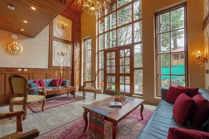A spacious living room with large windows, a chandelier, and a mix of traditional and modern furniture.