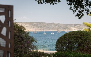 A coastal view with boats on the water, a rocky hillside in the background, and greenery in the foreground. - Thalè Residence Varkiza (Vari)