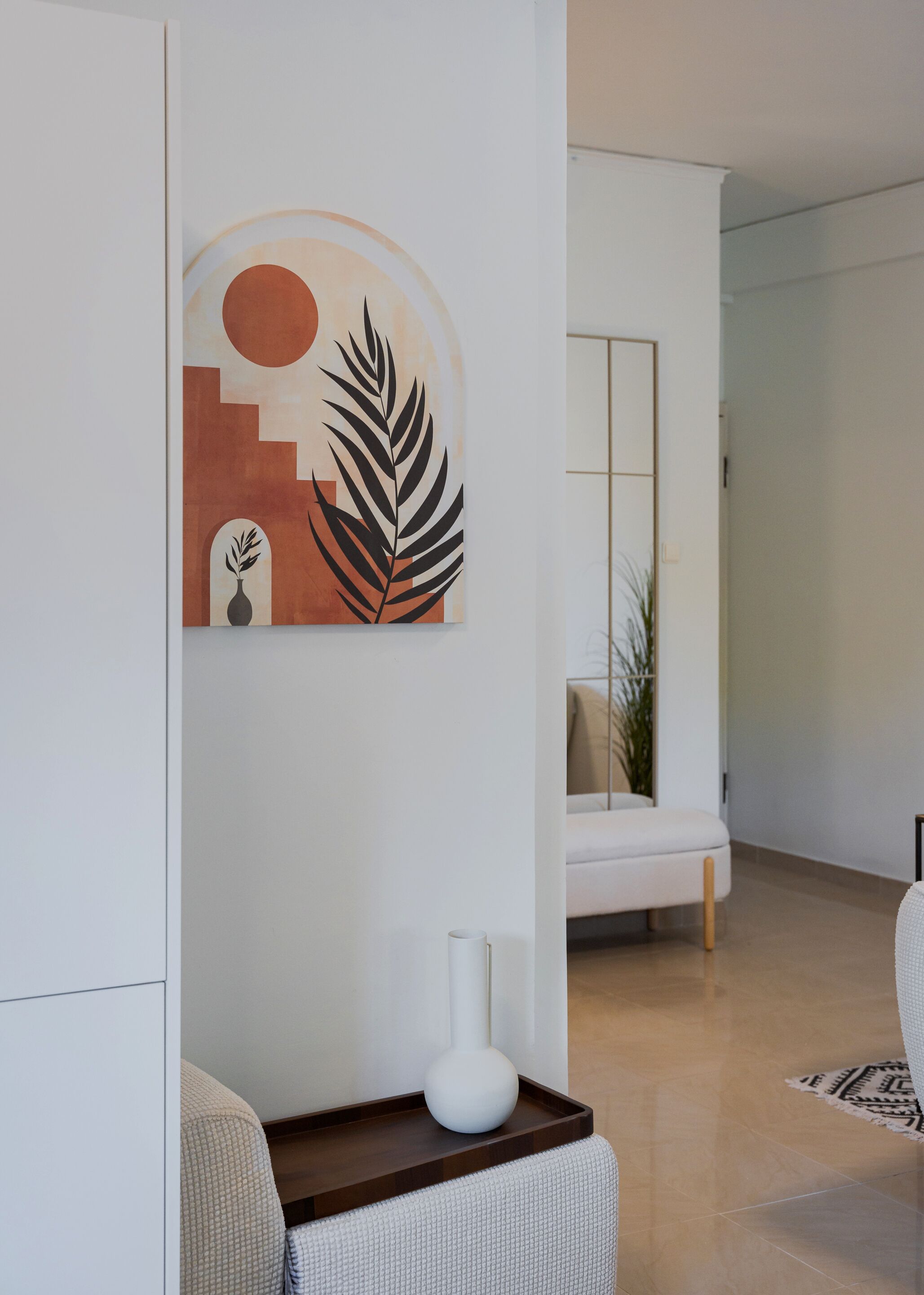 Un salon moderne au design minimaliste, comprenant un canapé blanc, une table basse avec un vase et une œuvre d'art abstraite accrochée au mur.