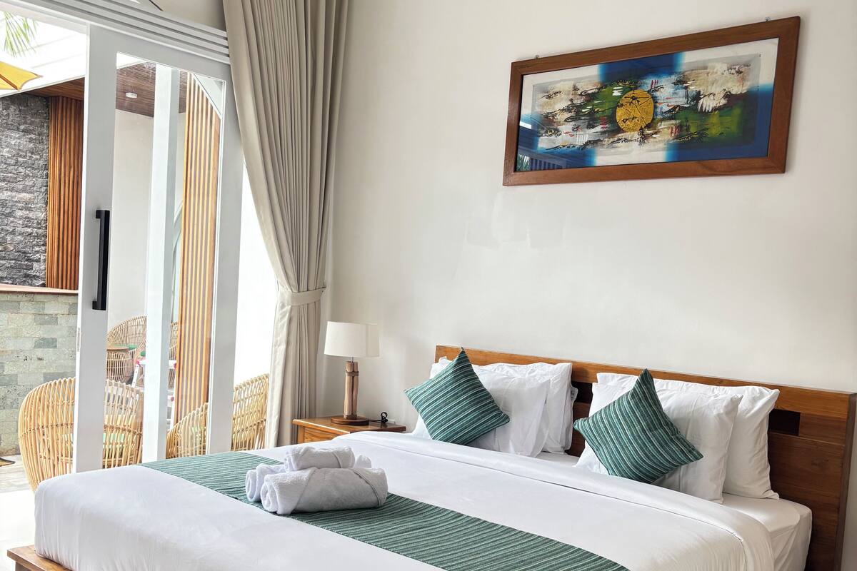 Una habitación de hotel con una cama grande, cabecera de madera y un cuadro en la pared.