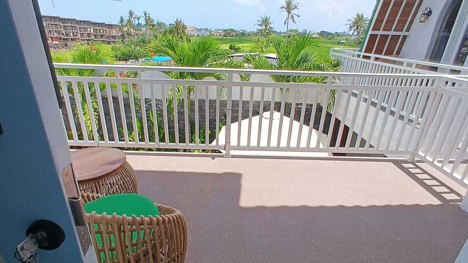 A balcony with a white railing, a small table, and a green chair.