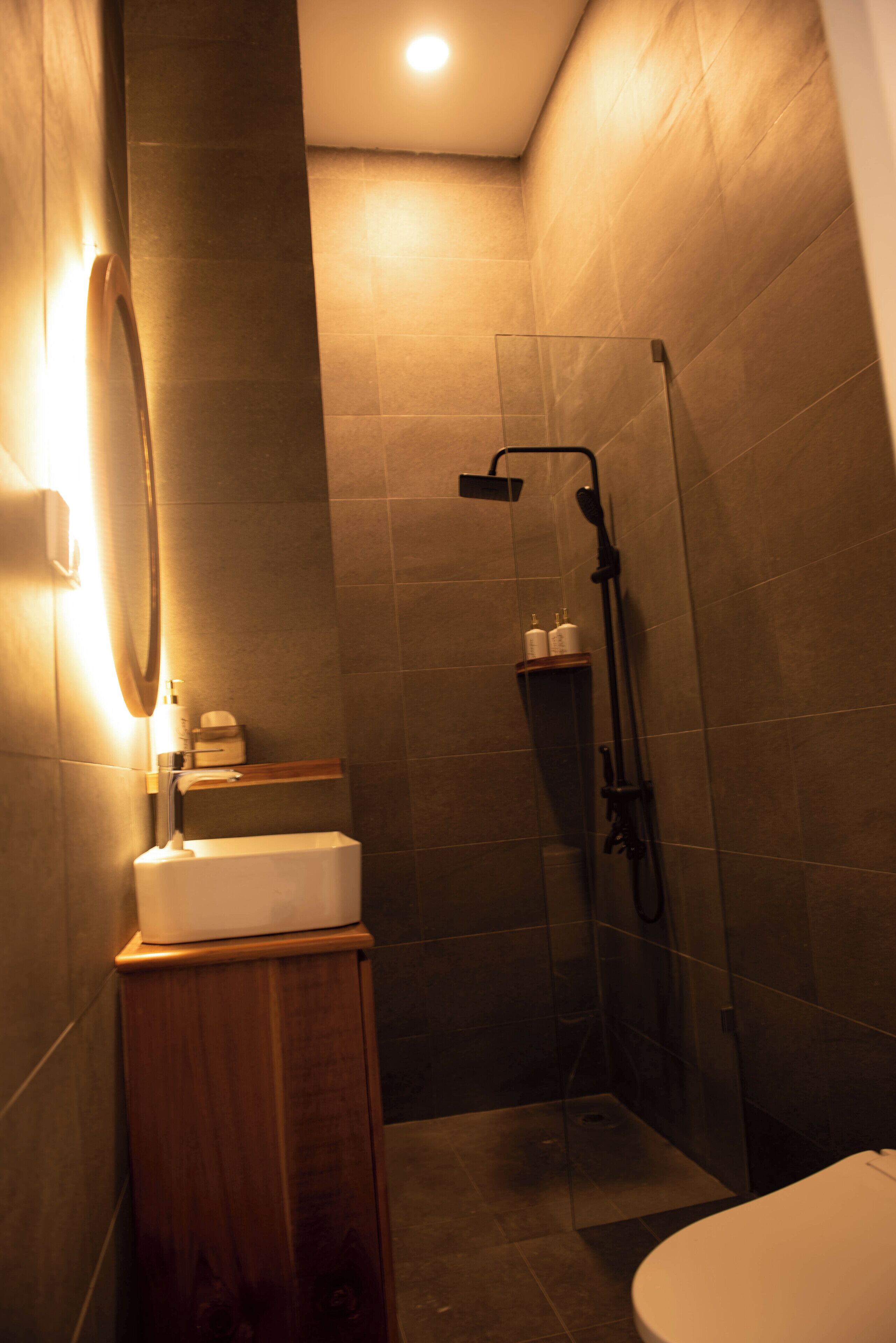 Une salle de bain moderne avec une douche à parois de verre, un meuble-lavabo en bois et un miroir fixé au mur.