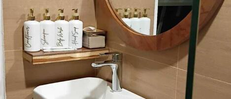 A bathroom with a white sink, wooden vanity, and a round mirror.